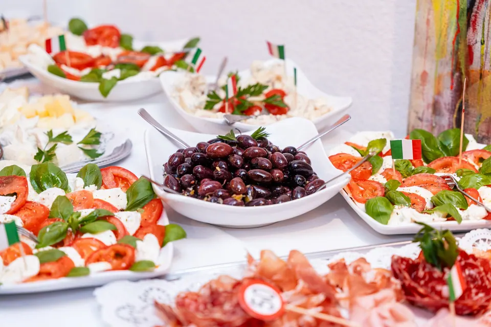 Italienisches Buffet mit Caprese, Oliven, Schinken und kleinen Italien-Fähnchen