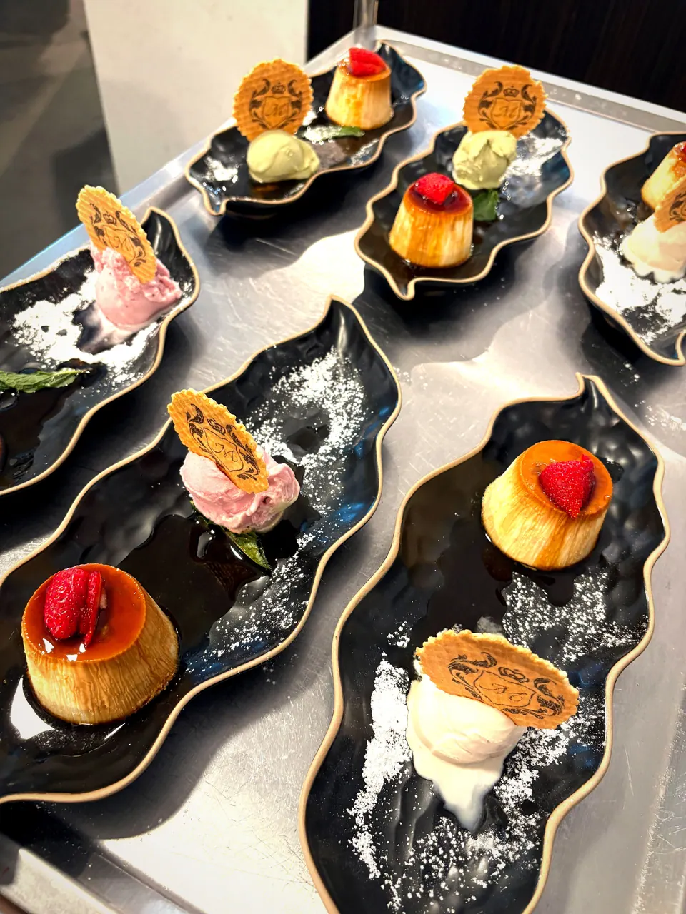 Dessertplatten mit Crème caramel, Eis, Waffeln und Beeren, angerichtet zum Servieren