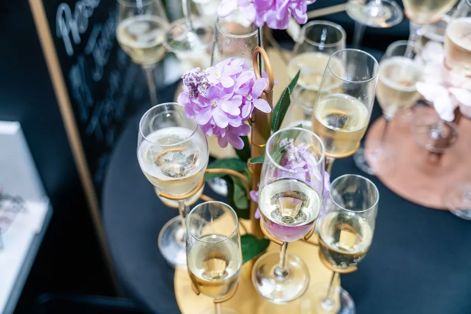 Ein Turm aus Proseccogläsern mit lila Blumen, angerichtet für den Empfang in der Markthalle