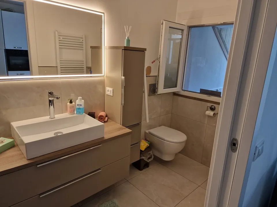 Badezimmer mit Waschbecken, Spiegel und Handtuchheizung