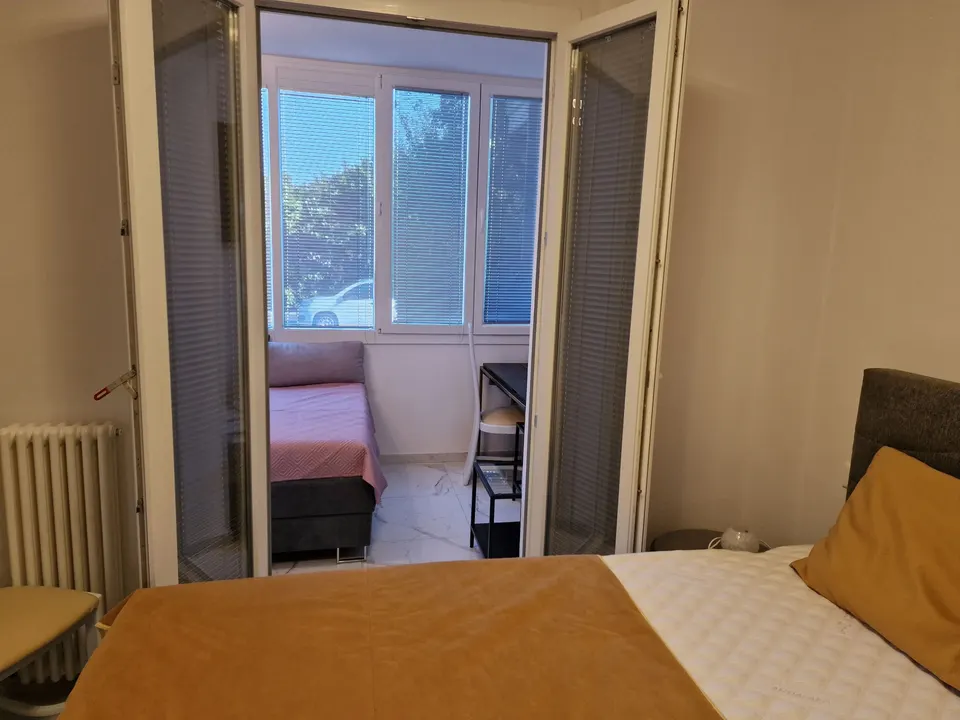 Zweites Schlafzimmer mit Bett, Sessel und Fenster
