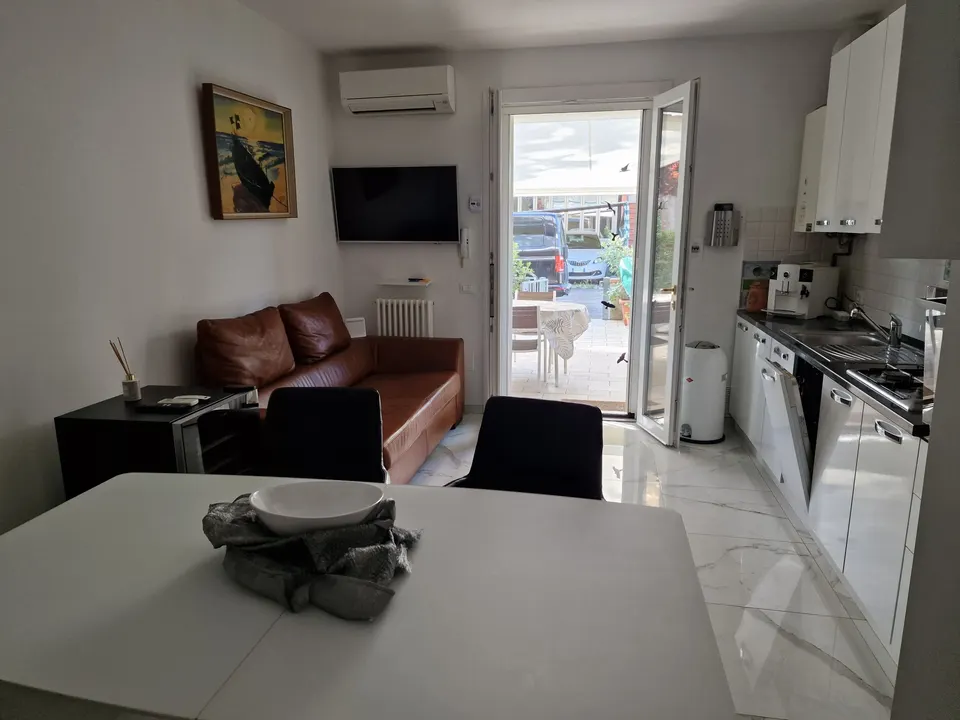 Wohnzimmer mit braunem Ledersofa, Fernseher und Blick zur Terrasse