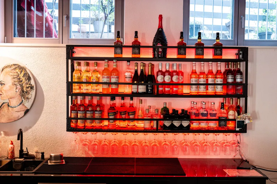 Das beleuchtete Regal an der Bar voller Aperol, Spritz und Prosecco
