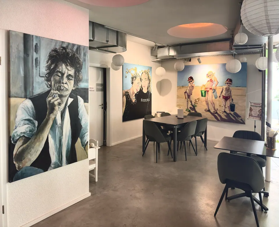 Tische in der Markthalle, an der Wand große Porträts in Öl